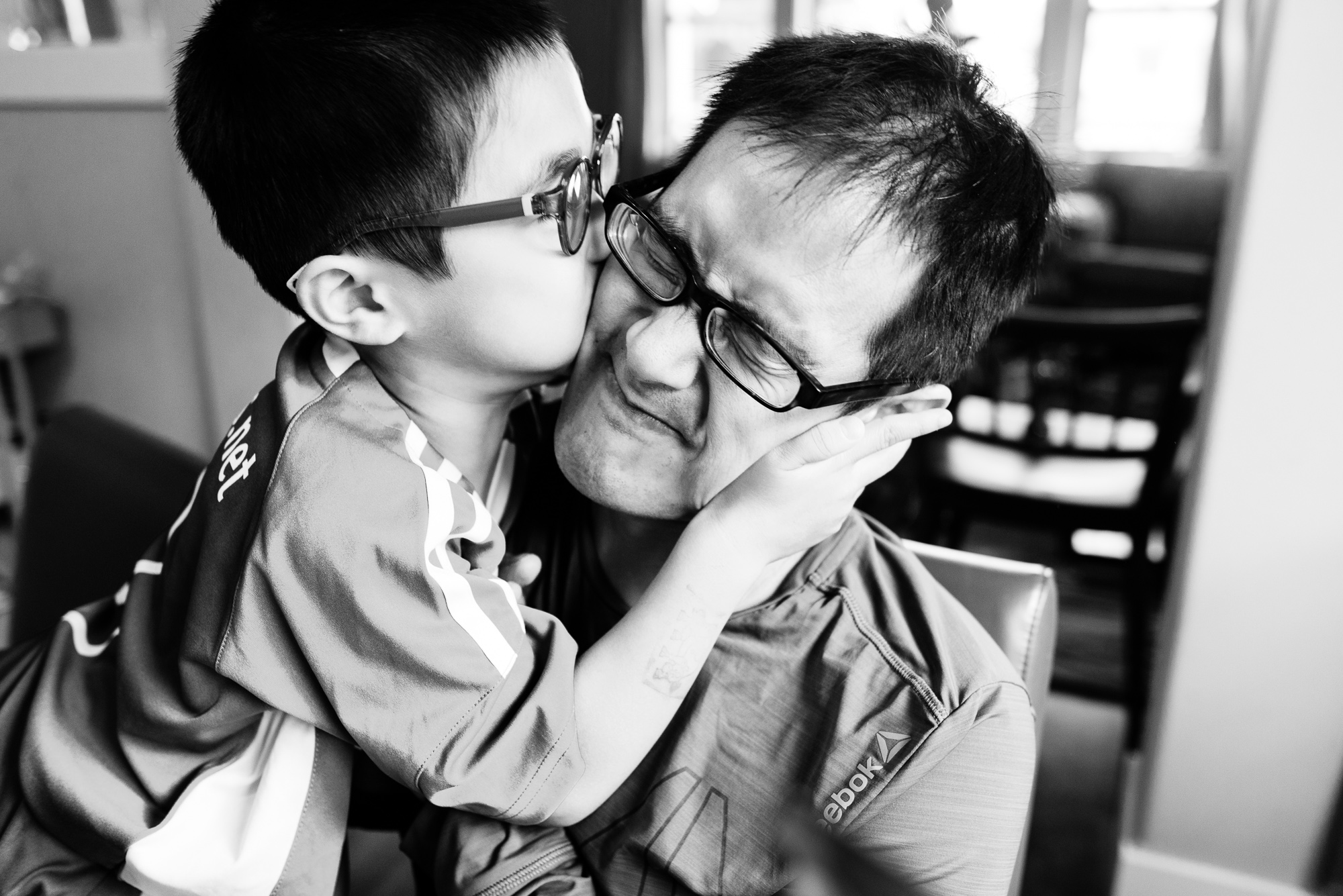 son kissing father - documentary family photography
