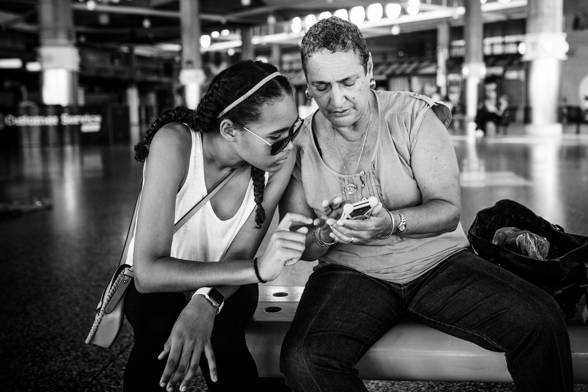 older woman and young girl look at phone together - documentary family photography