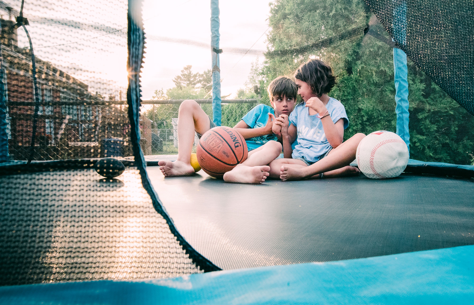 kids sitting together on trampoline - documentary family photography