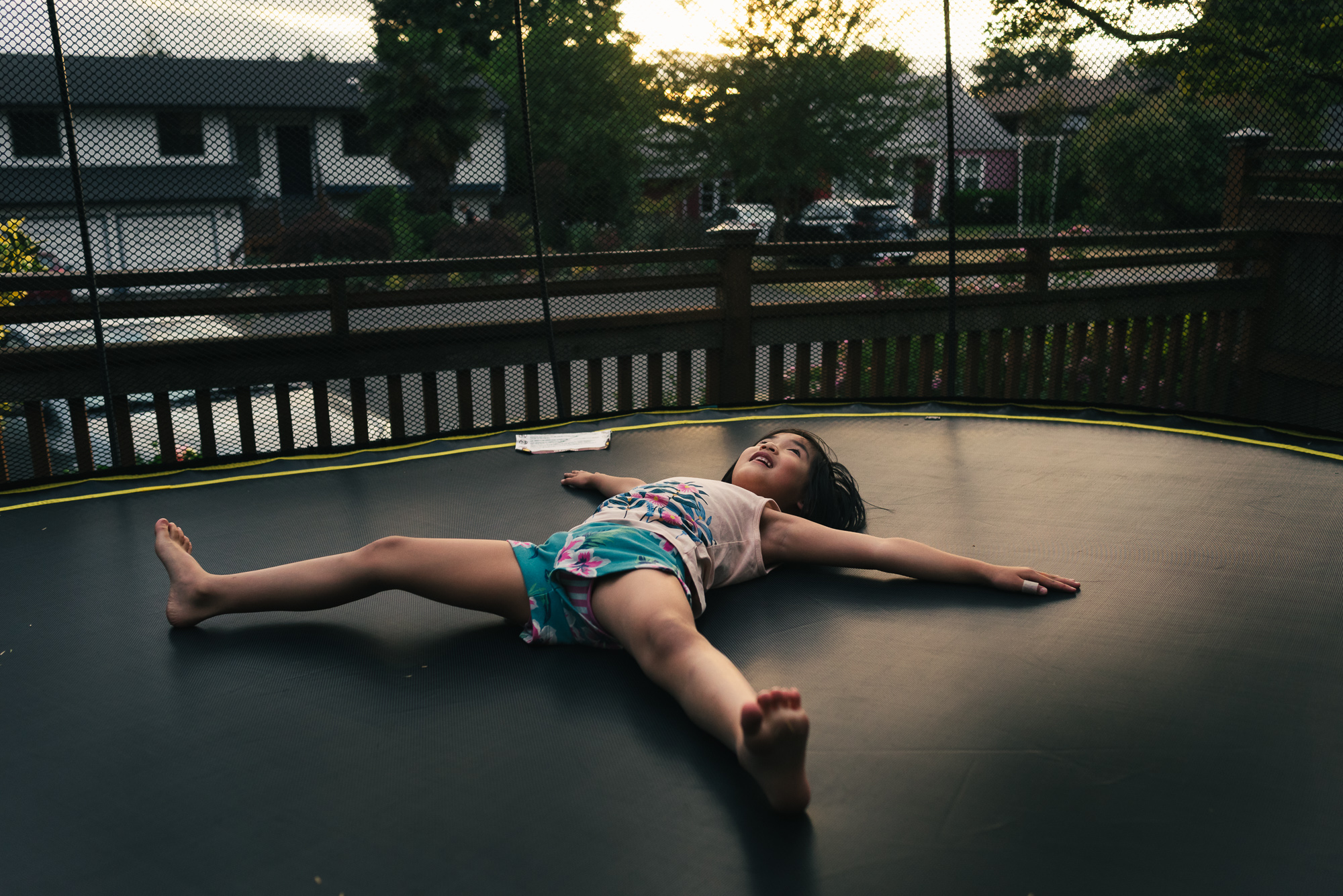 girl laying on trampoline - documentary family photography