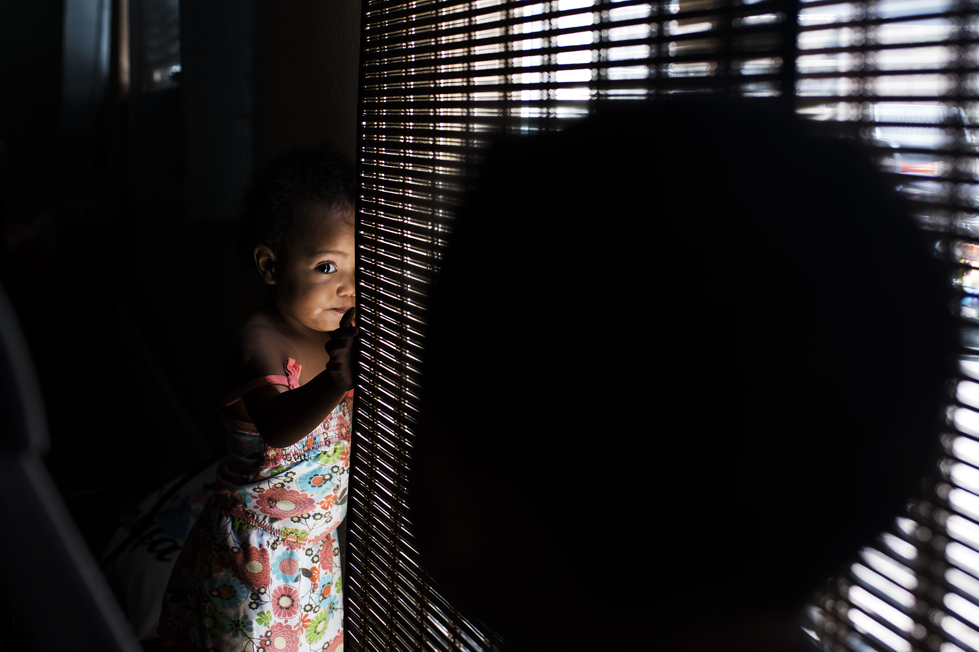 girl looking past blinds - documentary family photography