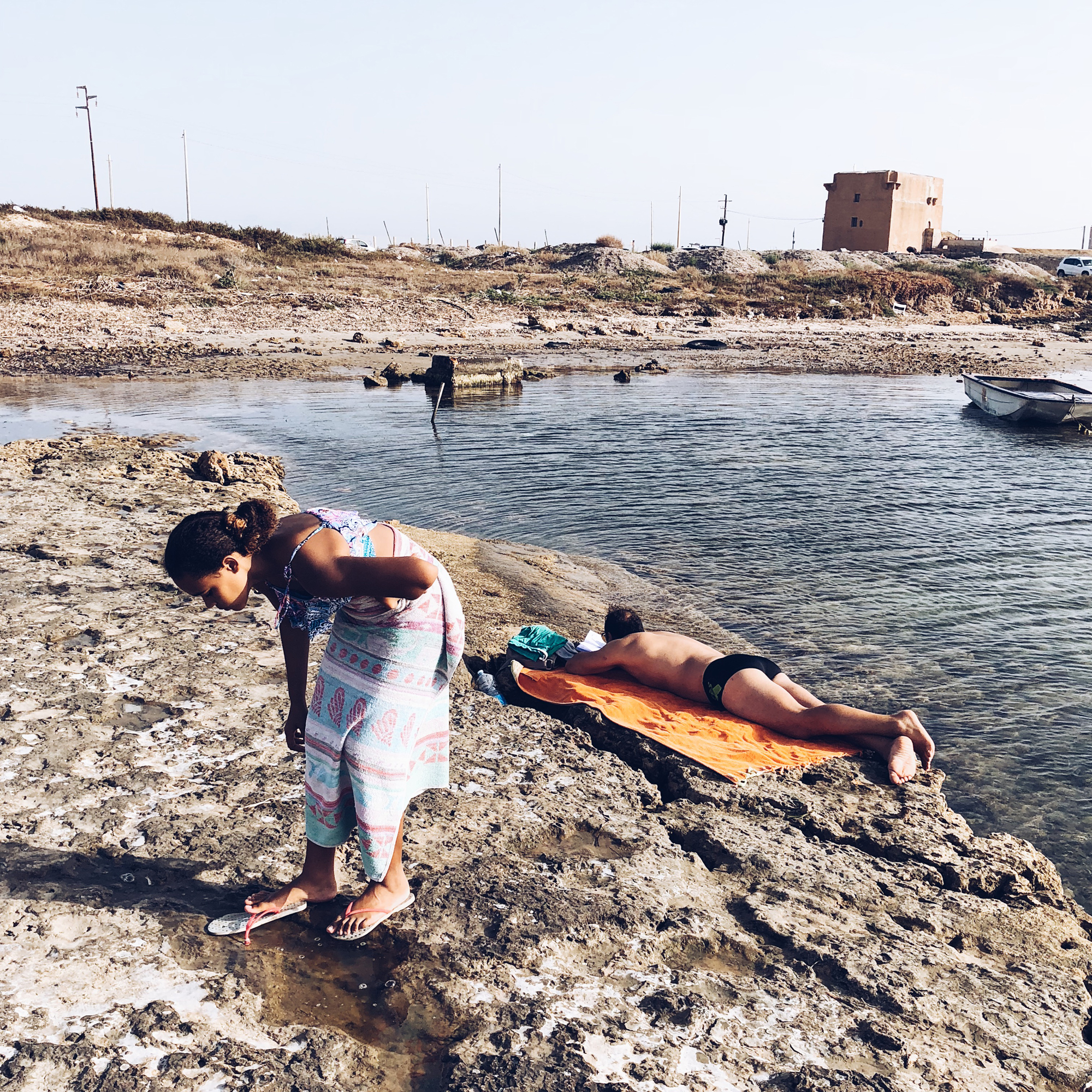 girl bending over on rocky shoreline - documentary family photography