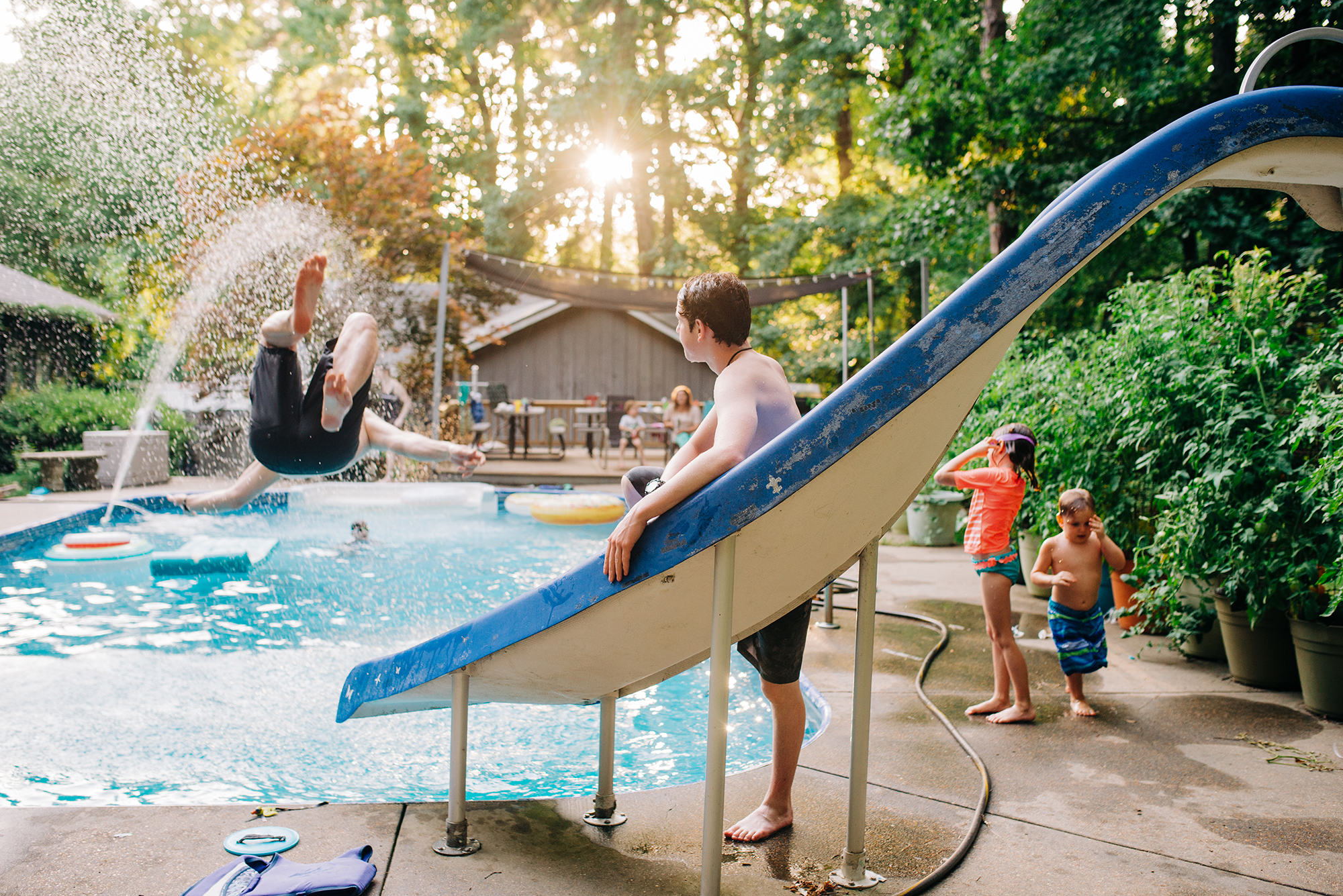 boy going down slide into pool - documentary family photography
