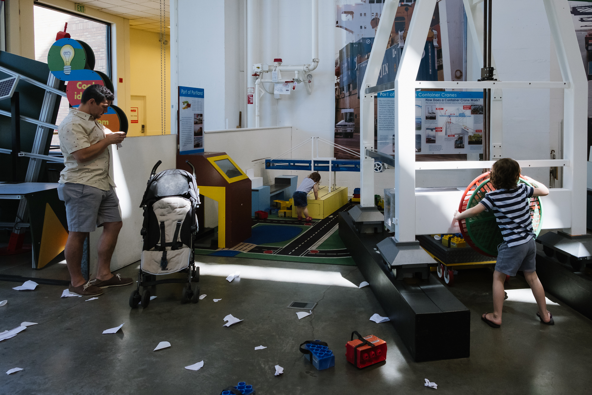 kids play at museum exhibit while father checks phone - documentary family photography