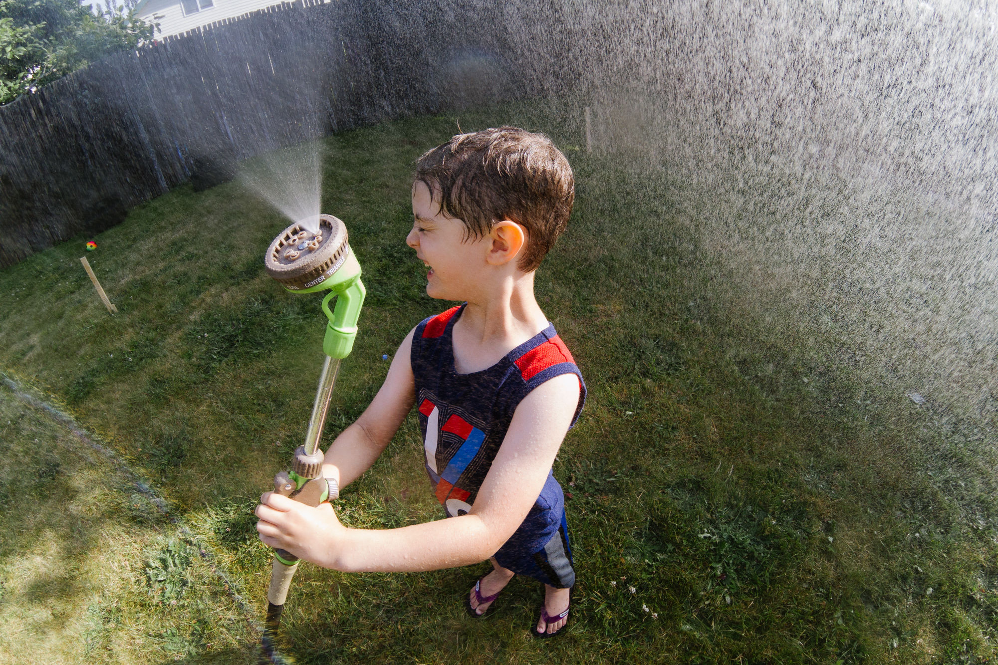 boy playing with garden hose - documentary family photography