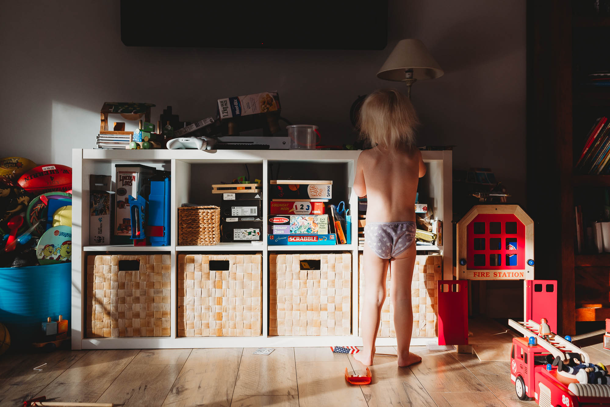 child standing at shelves in sunlight -documentary family photography