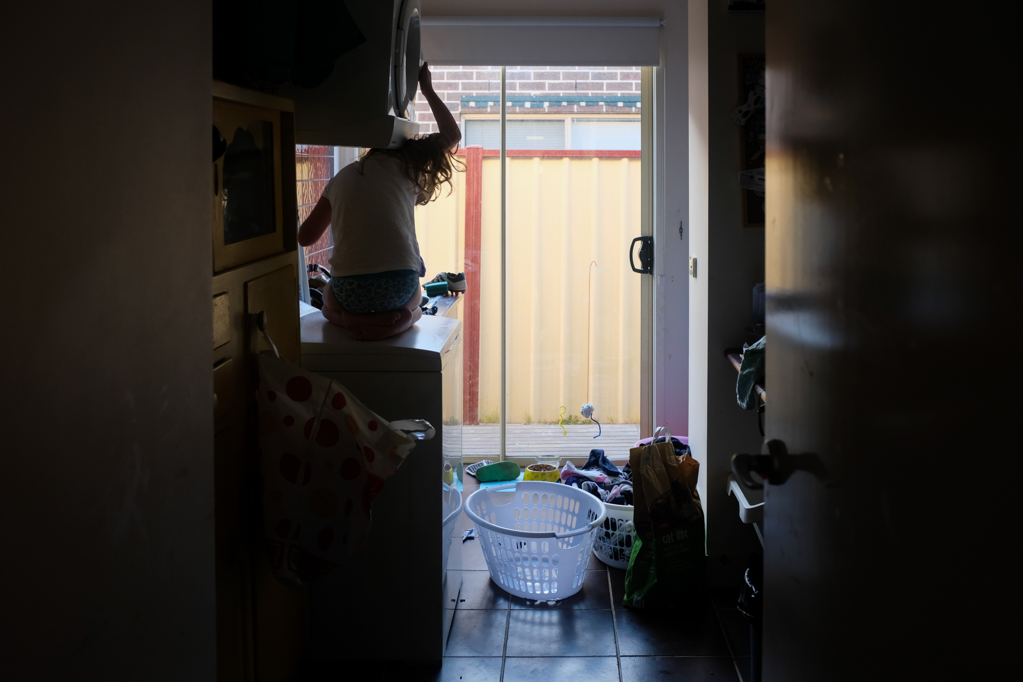 kid climbing in laundry cabinet - documentary family photography