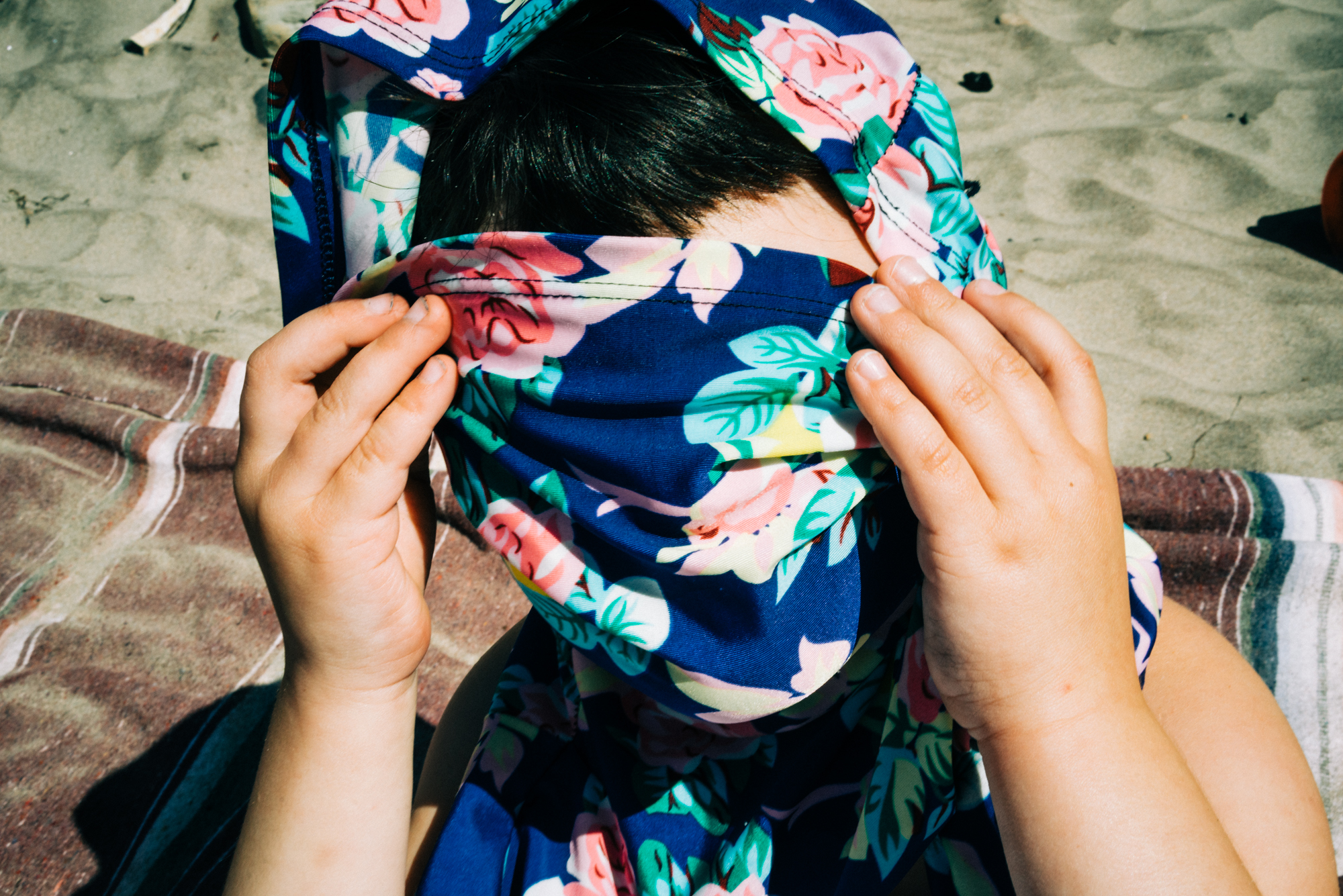 girl hiding behind floral scarf - documentary family photography