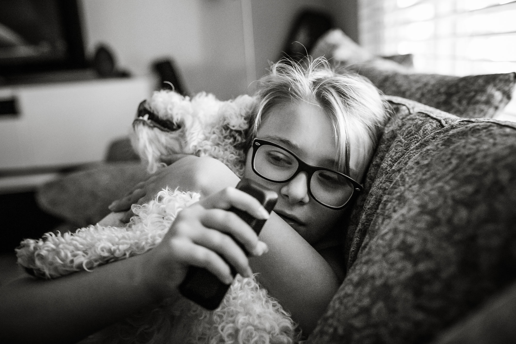 girl snuggled with dog on couch - documentary family photography