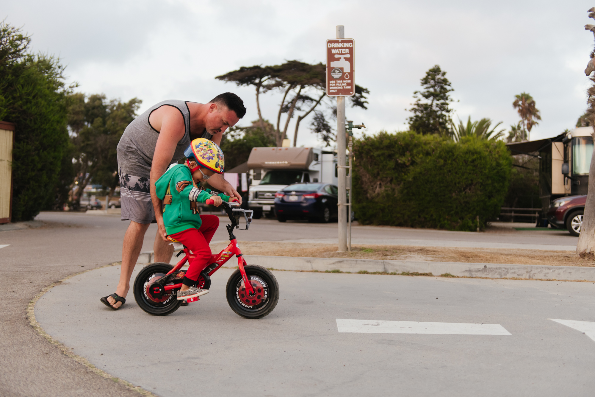 father helps child on bike - documentary family photography