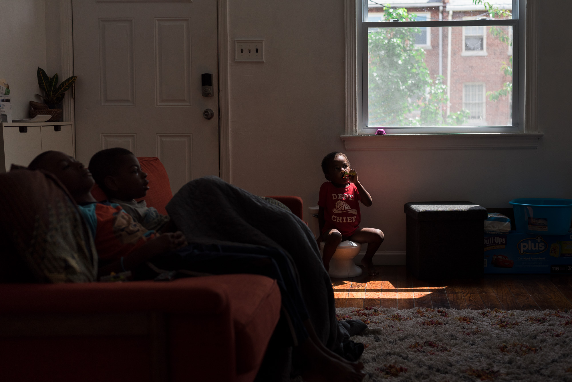 kid sitting in a spot of light - documentary family photography