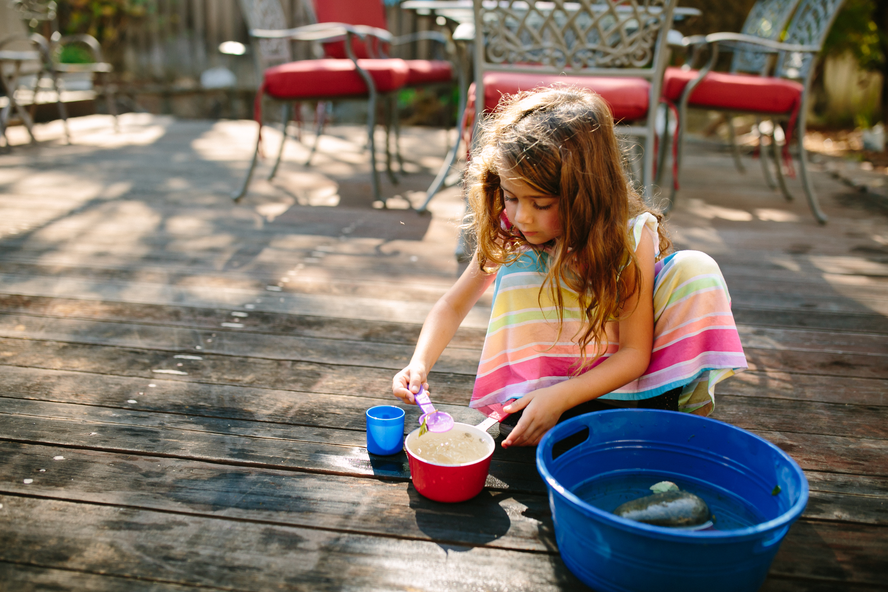 girl plays with water and cups - documentary family photography