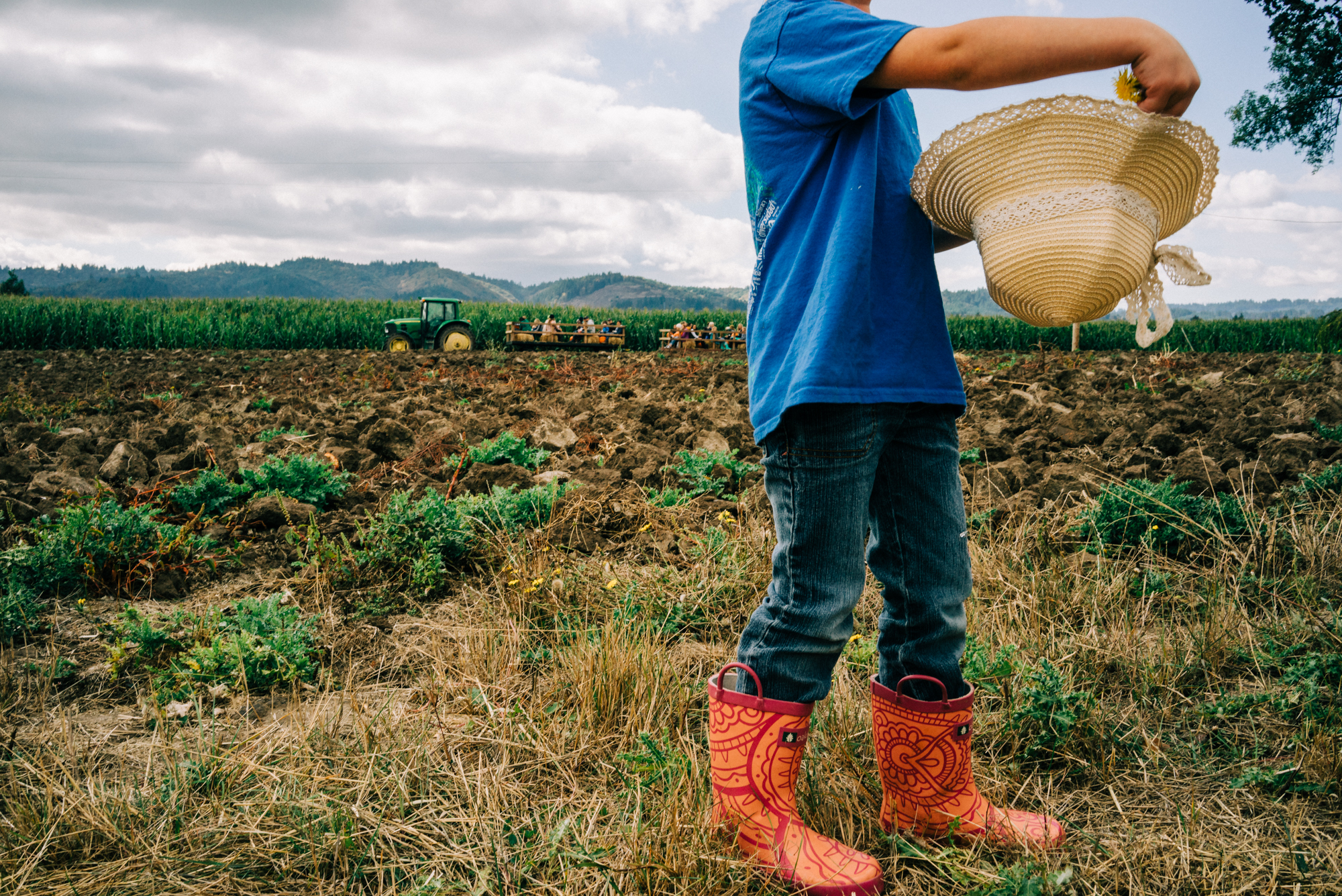 kid in field with books and hat - documentary family photography