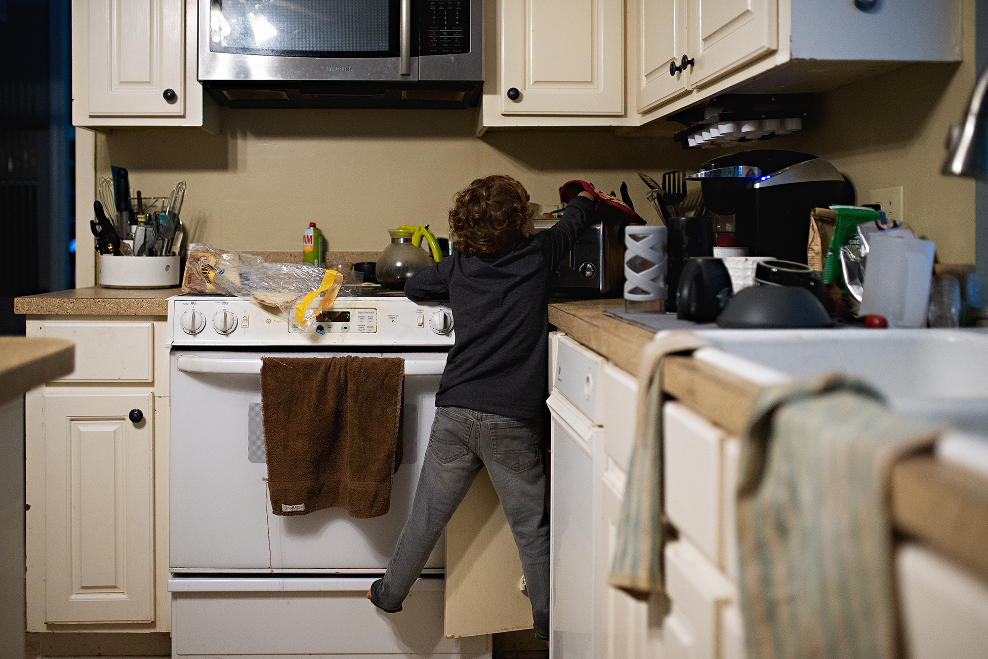 boy climbing on counter - documentary family photography