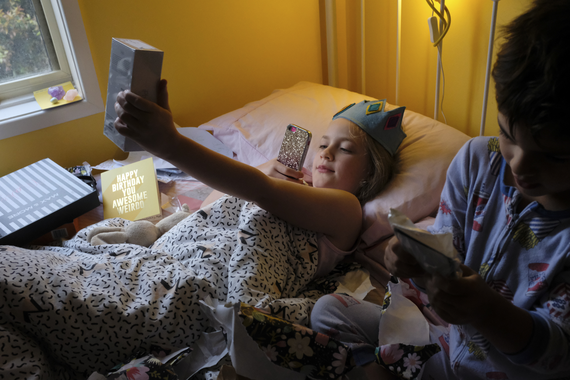 girl wearing birthday crown takes iphone photo - documentary family photography