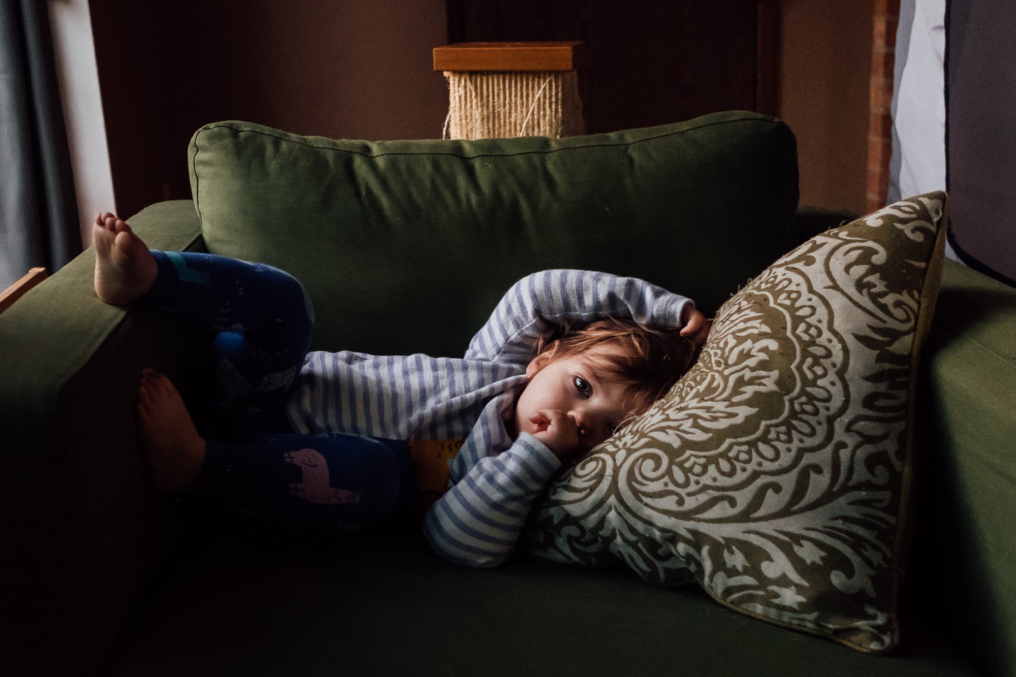 girl curled in chair sucking thumb-documentary family photography