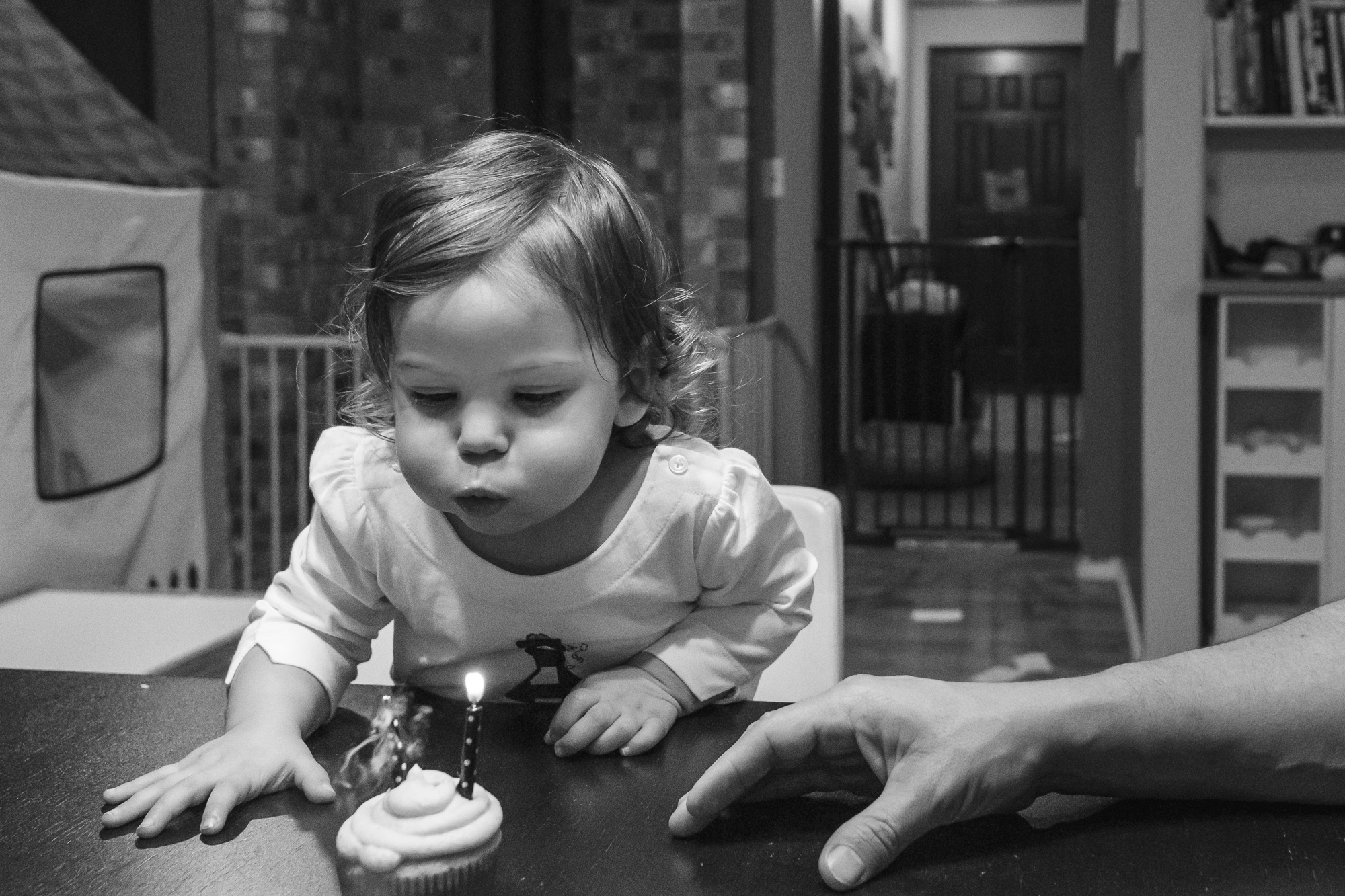 girl blows out candles on cupcake - documentary family photography