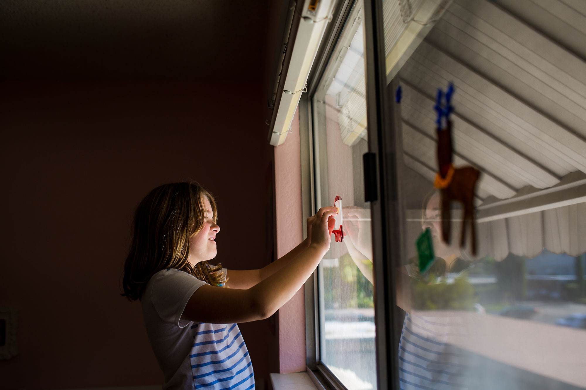 girl decorating window - documentary family photography