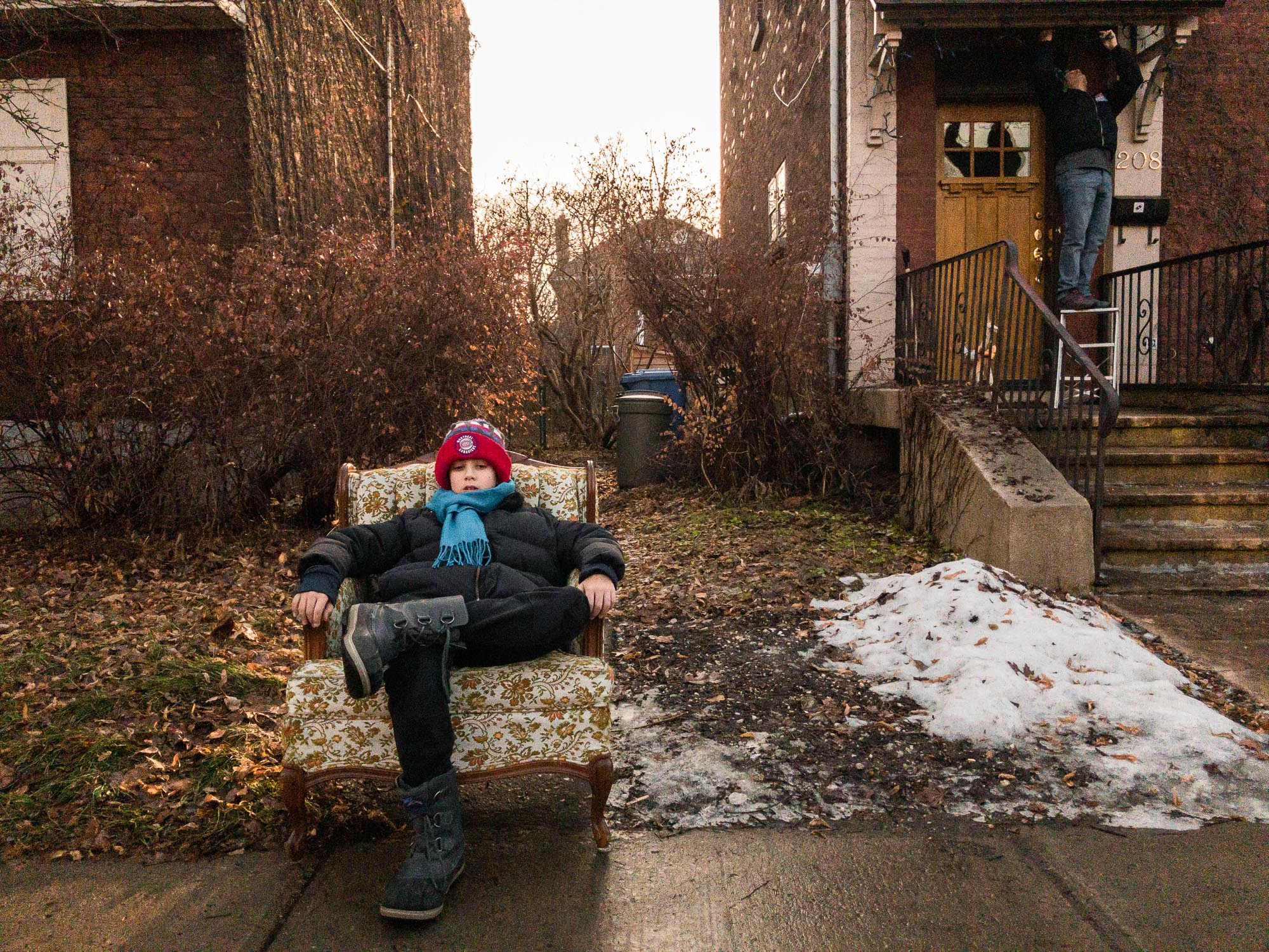 boy in chair left on sidewalk - documentary family photography