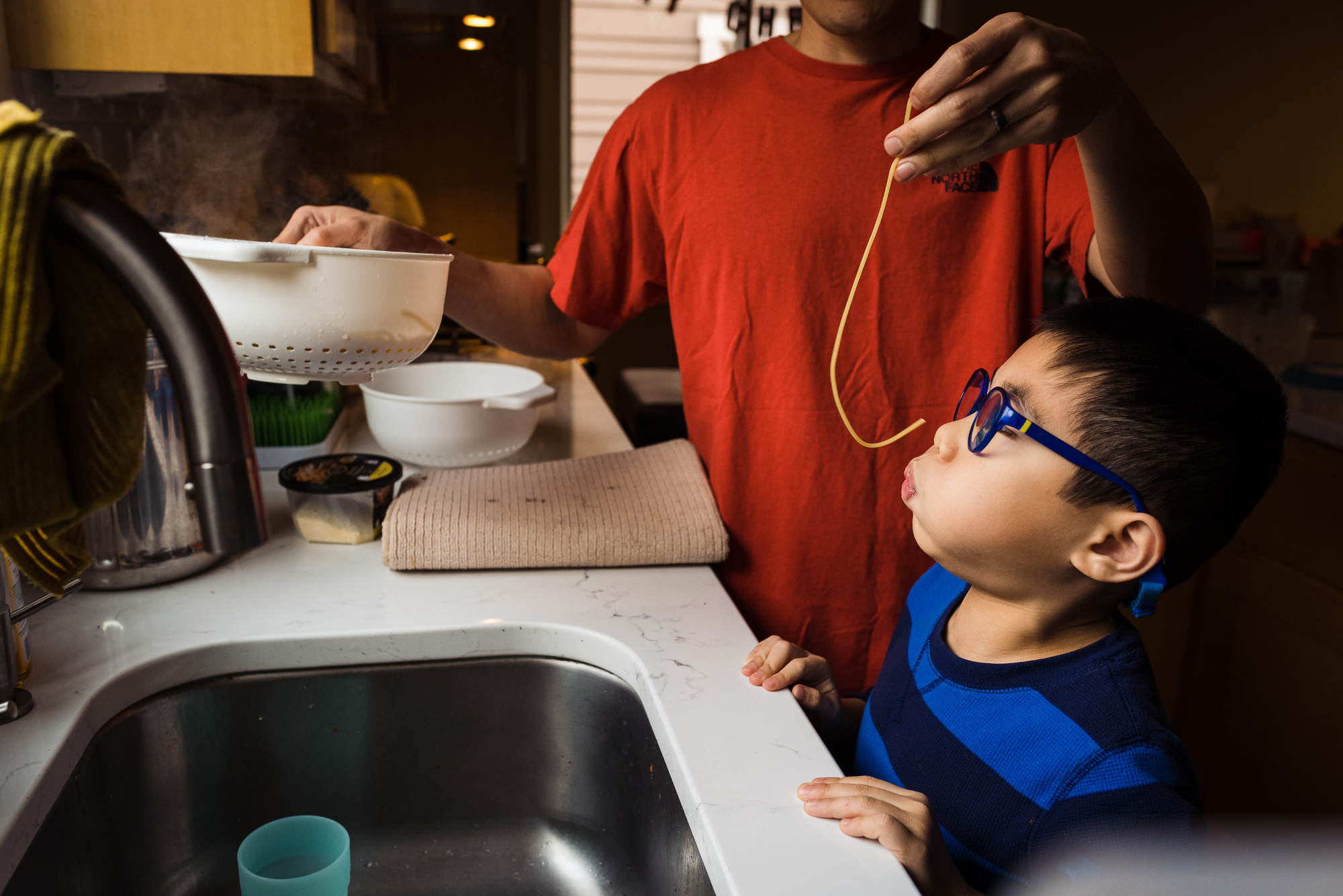 father feeding son noodles - documentary family photography