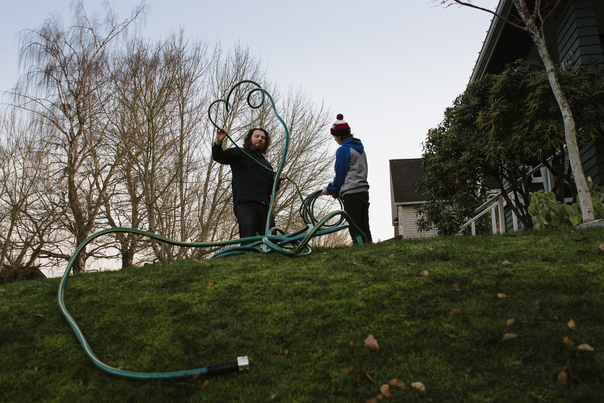 family untangling garden hose - documentary family photography
