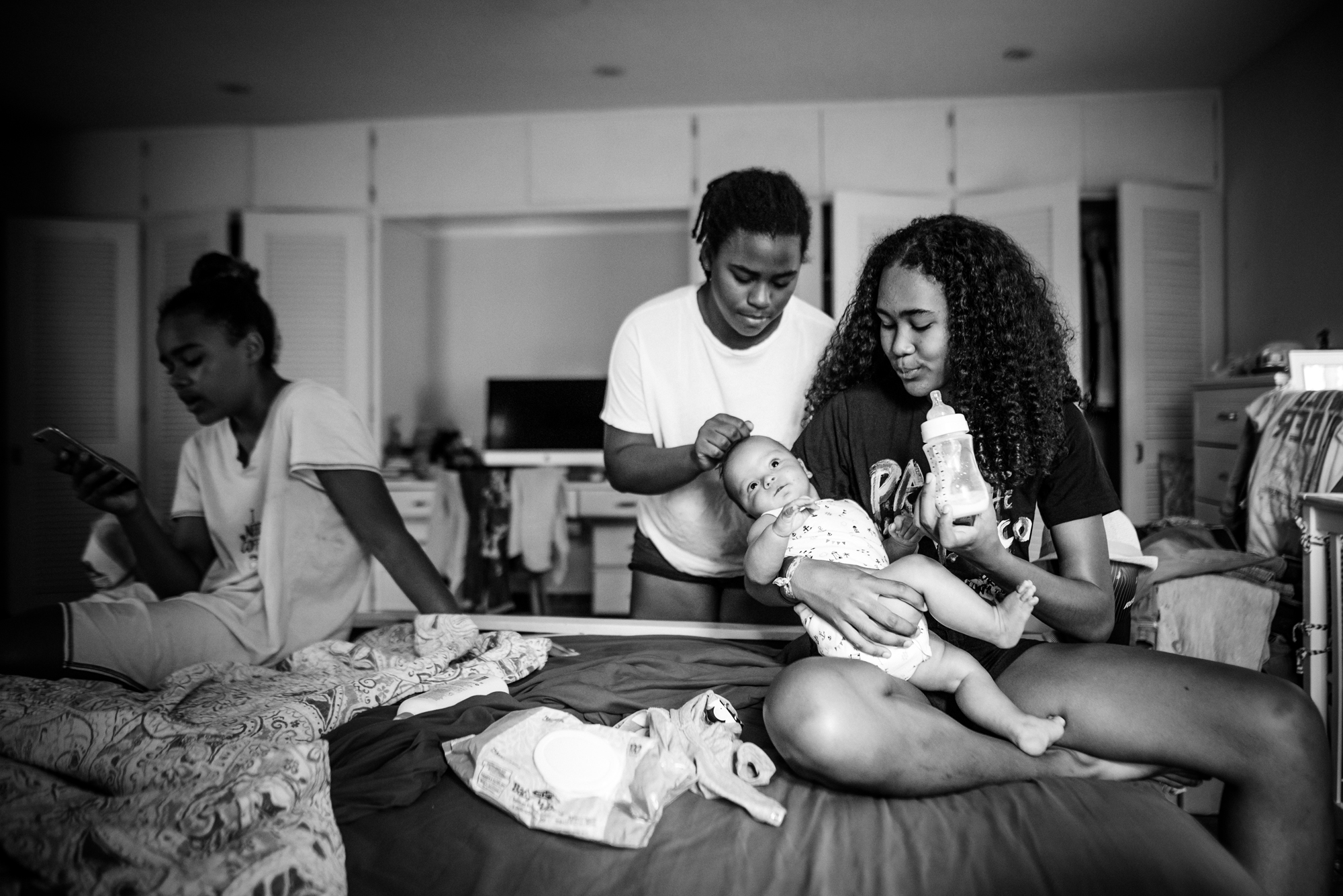 sisters feeding baby - documentary family photography