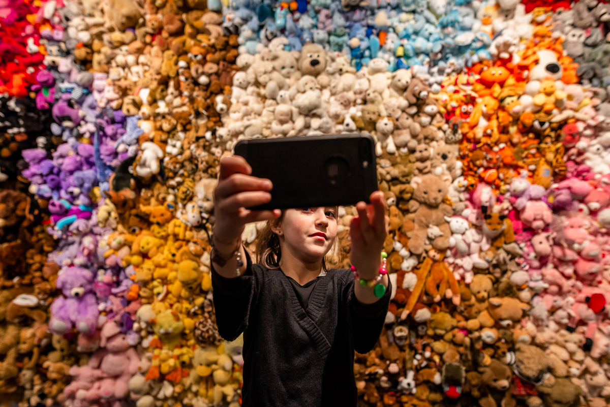 girl taking selfie at decorative wall - documentary family photography