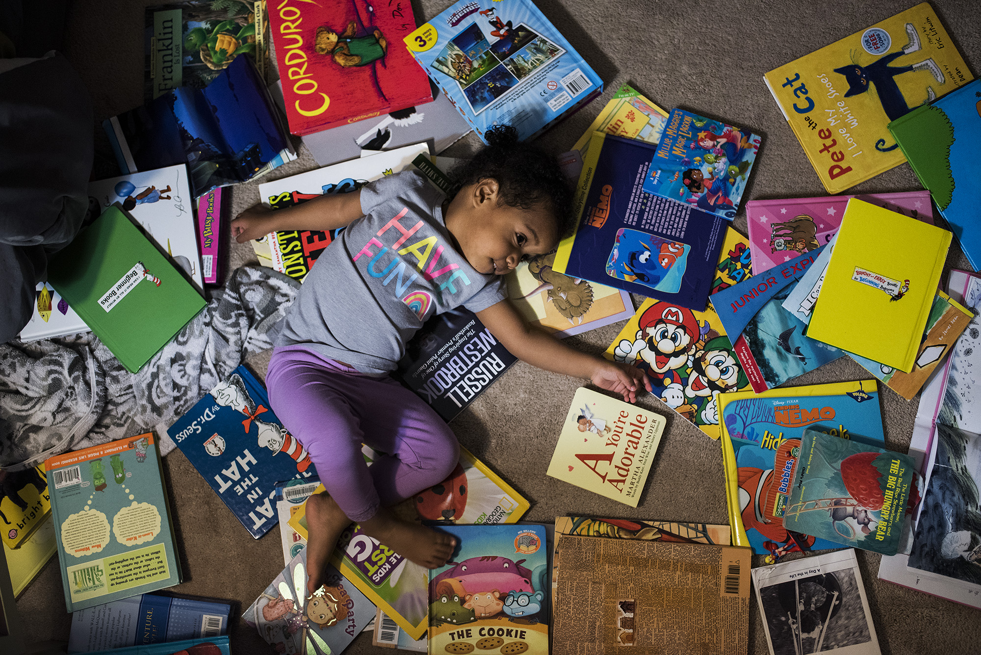 girl on floor surrounded by books - documentary family photography