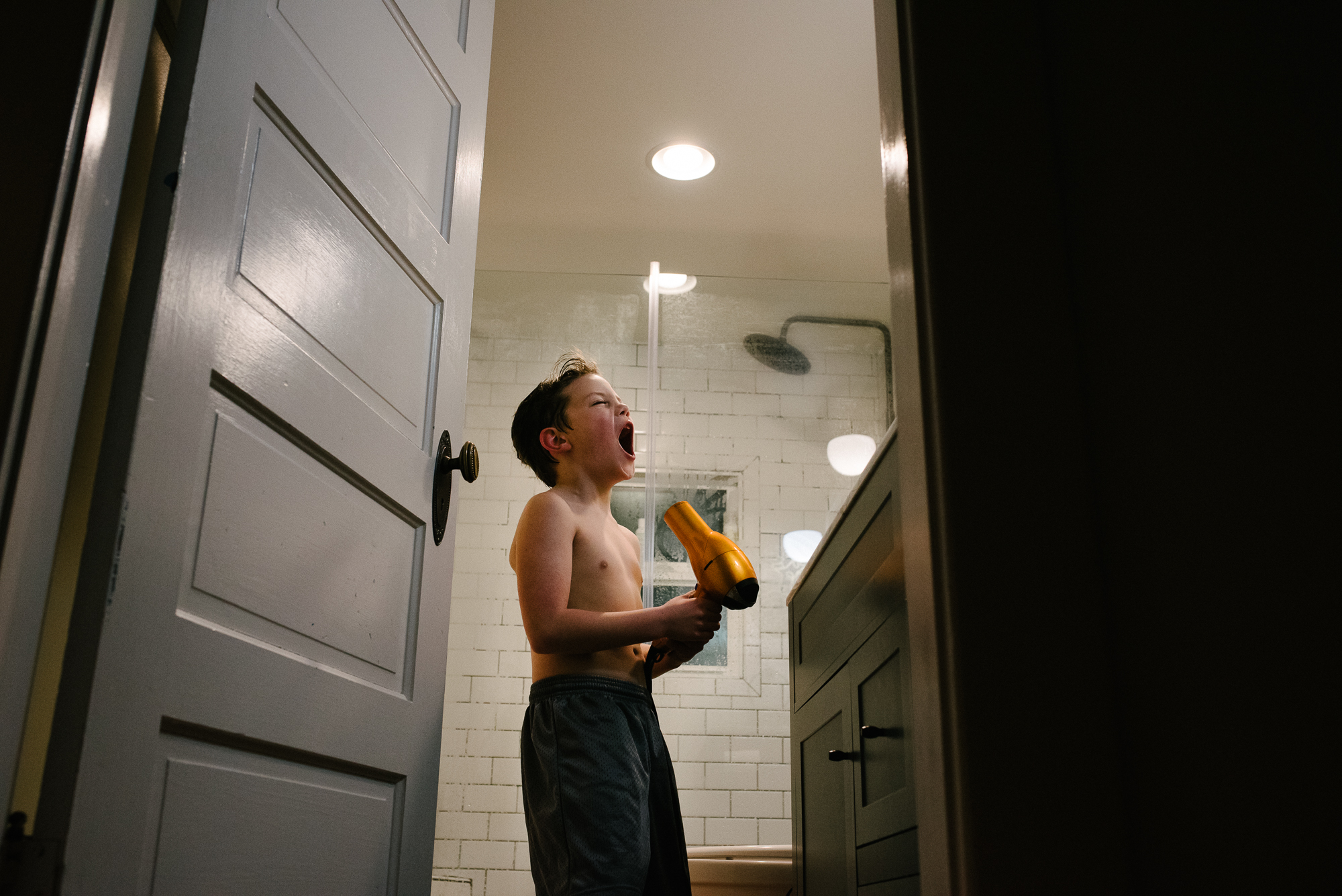 boy yelling into hair dryer - documentary family photography