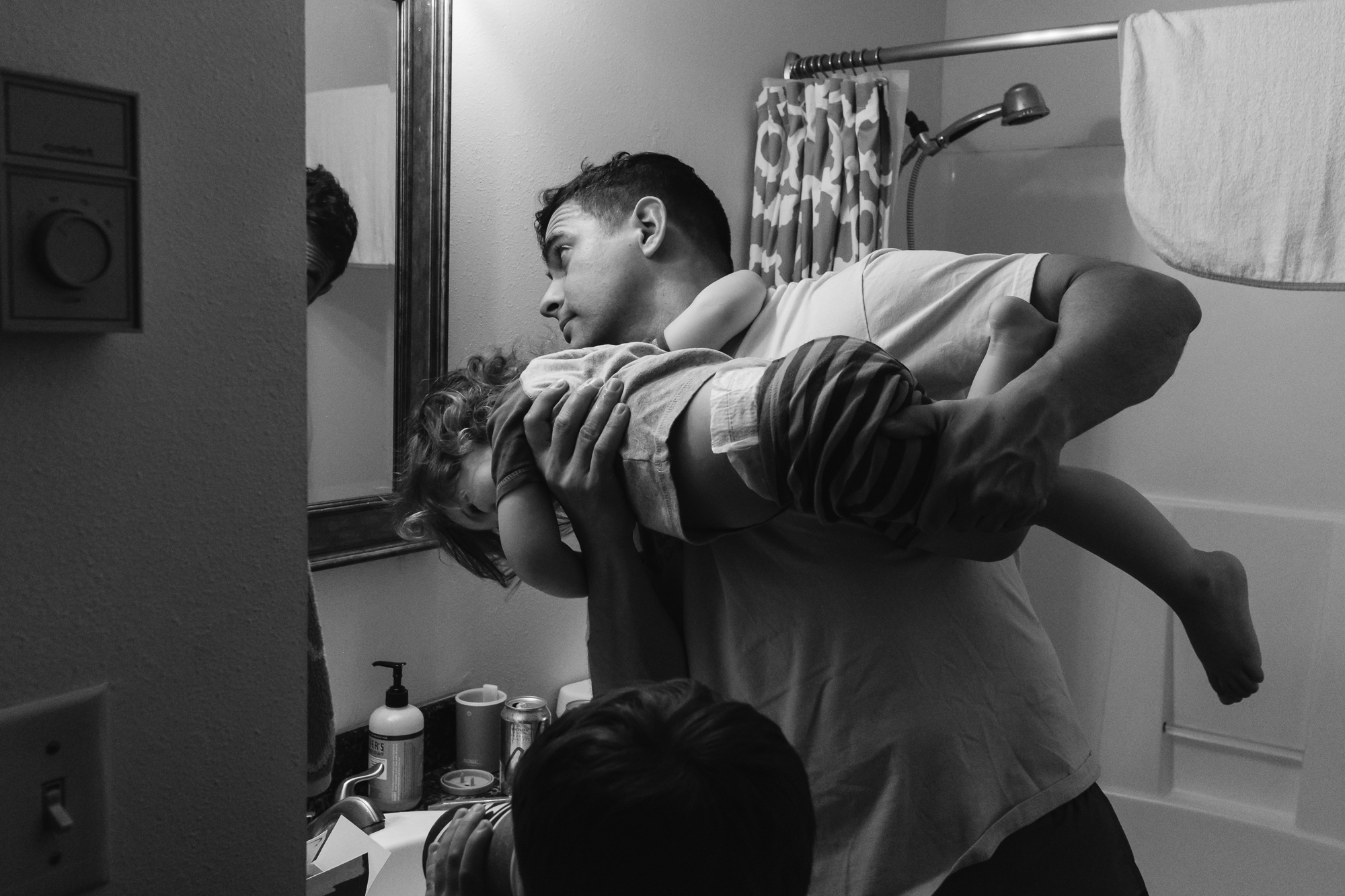 father holding daughter above sink - documentary family photography