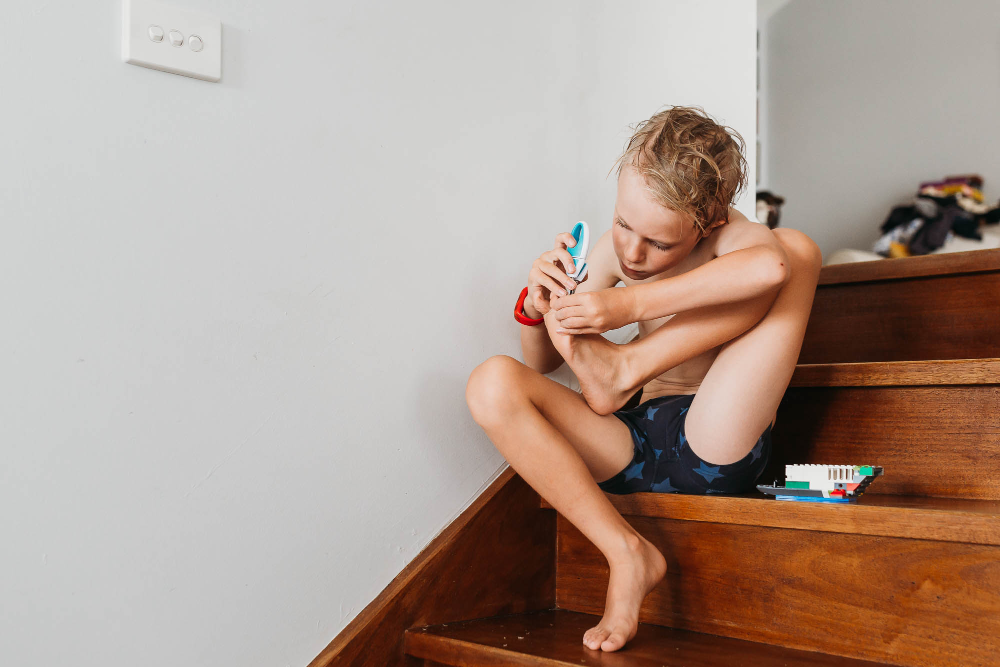 boy clipping toenails - documentary family photography