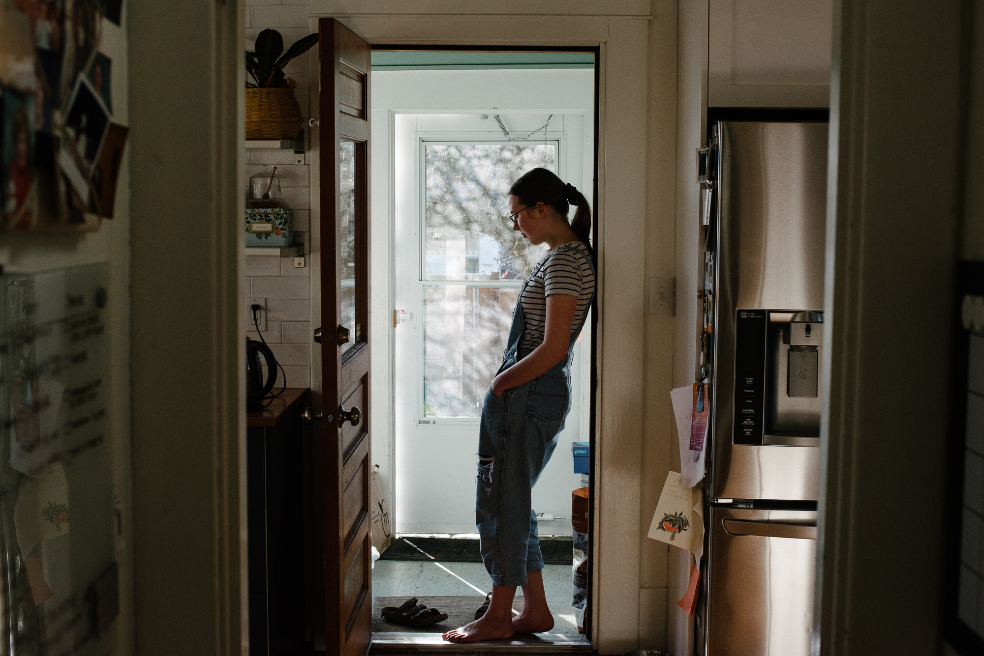 girl stands in doorway - documentary family photography
