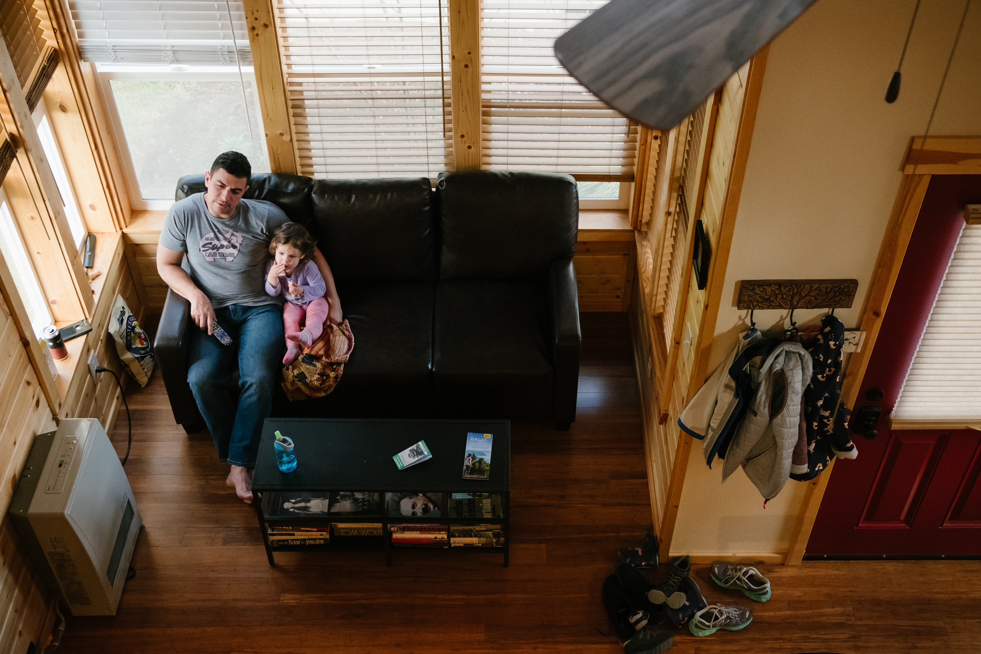 father and daughter watch TV on couch - documentary family photography