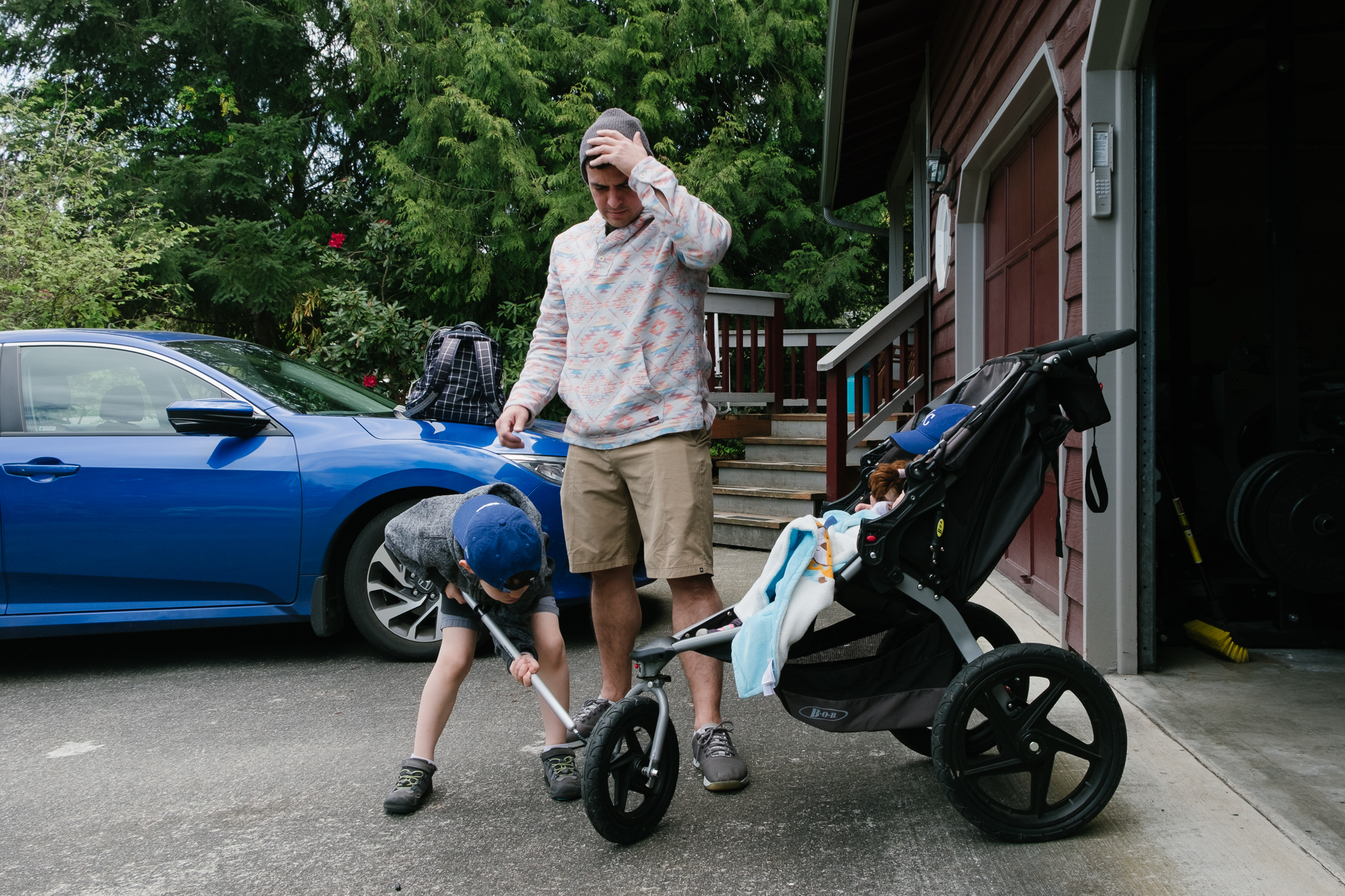 boy attempts to pump air into stroller tire - documentary family photography