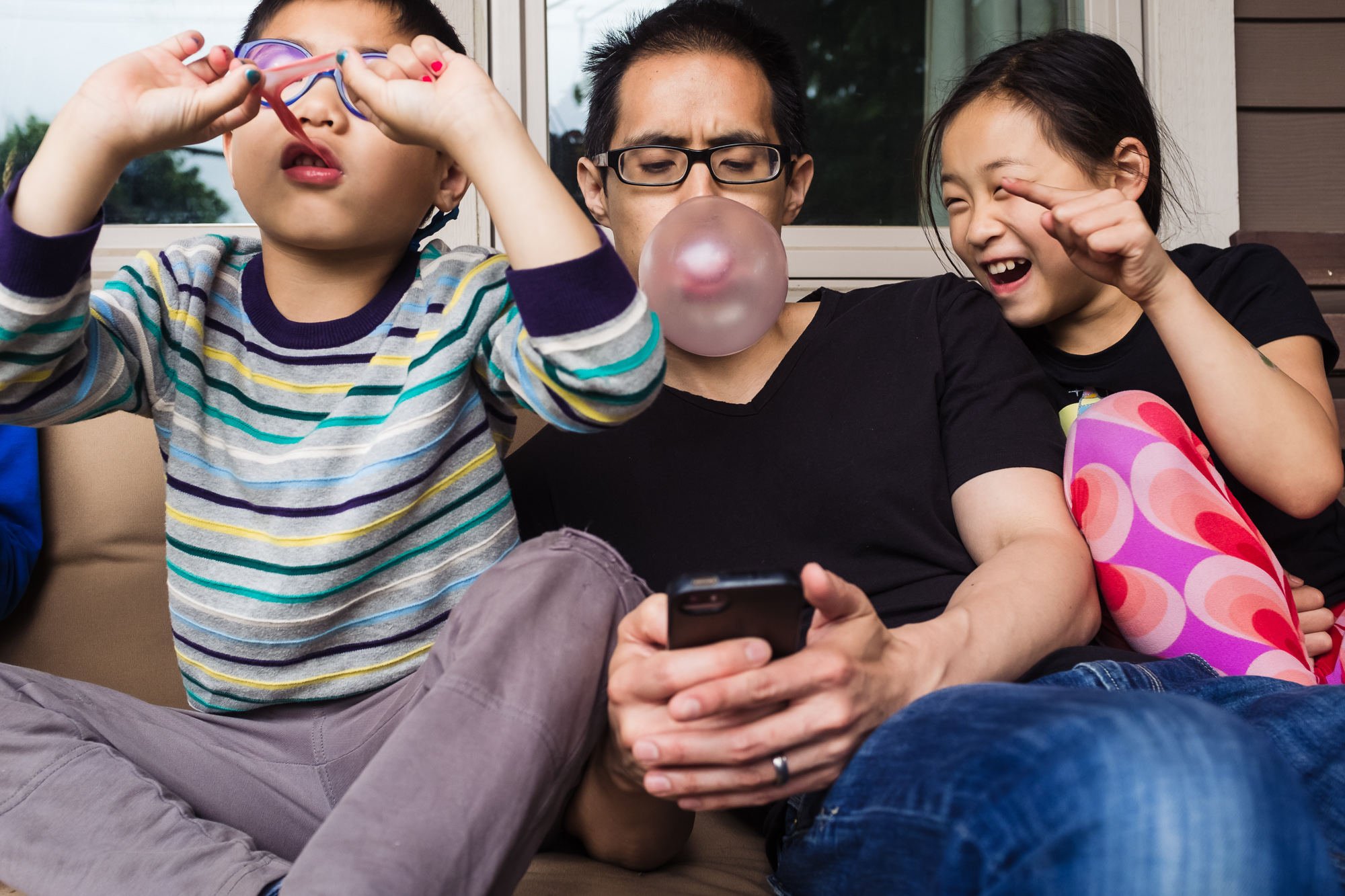 father and kids with phone and bubble gum - documentary family photography