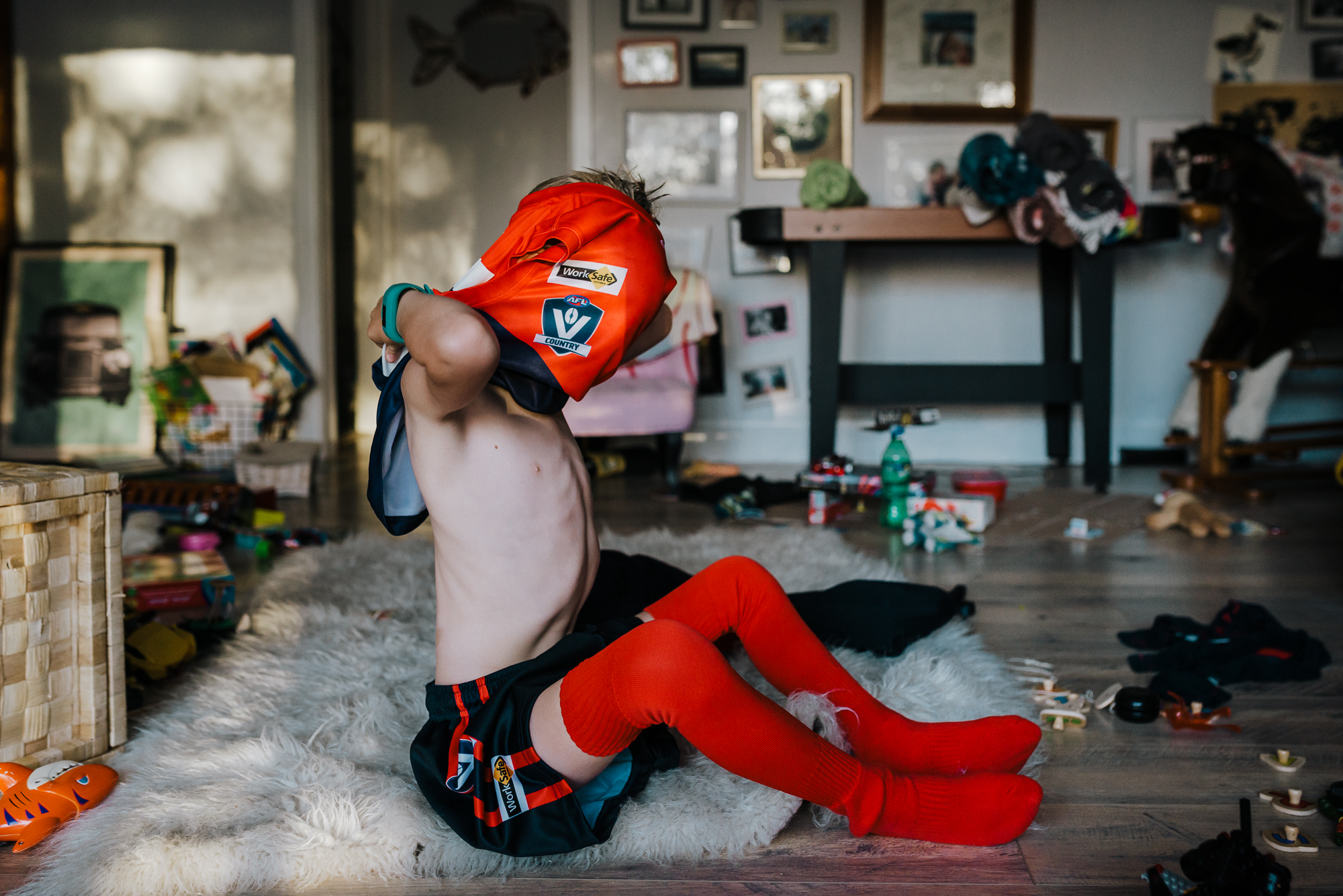Kid getting dressed in sports uniform - documentary family photography