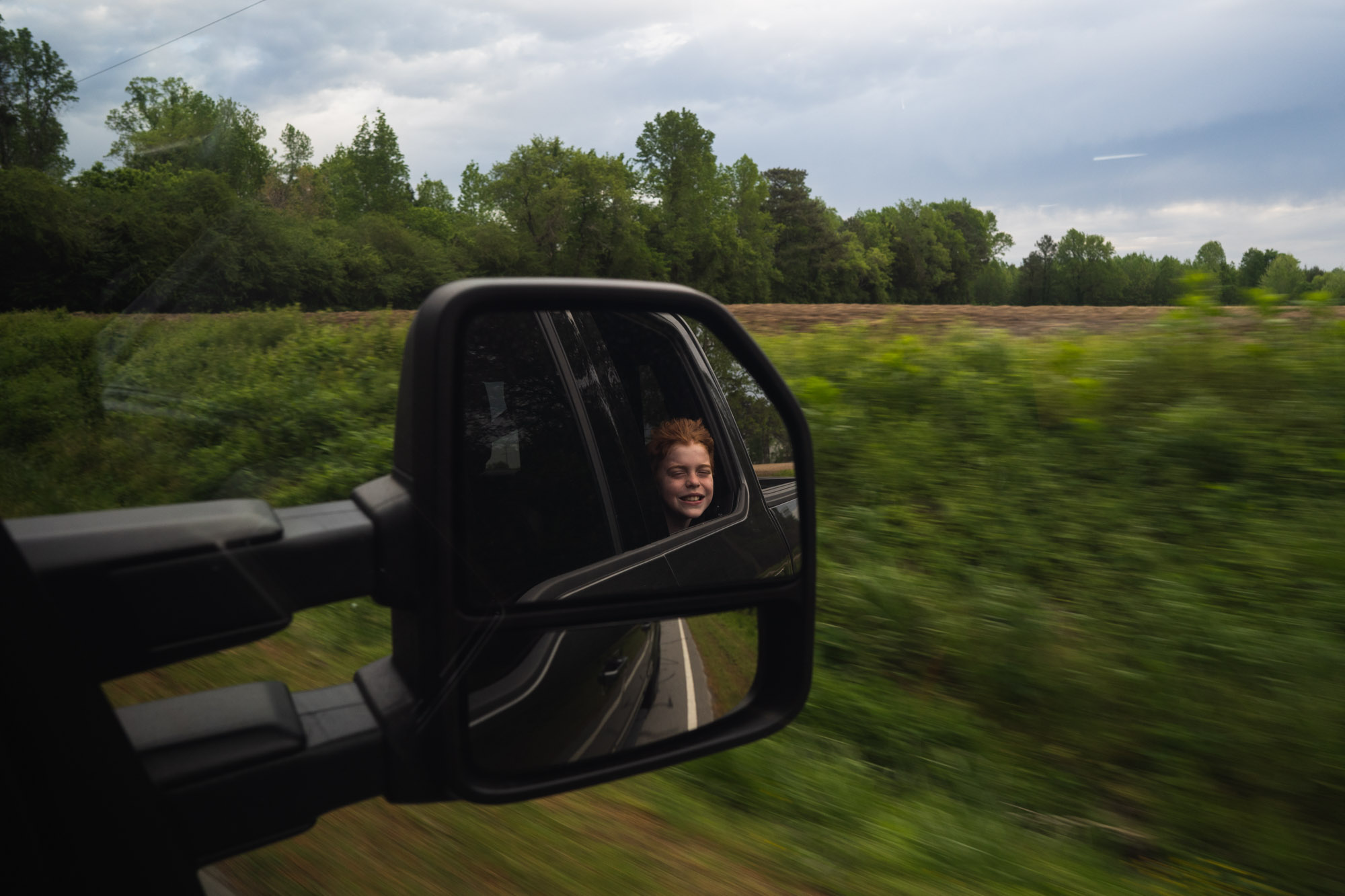 kid in rear view mirror - documentary family photography