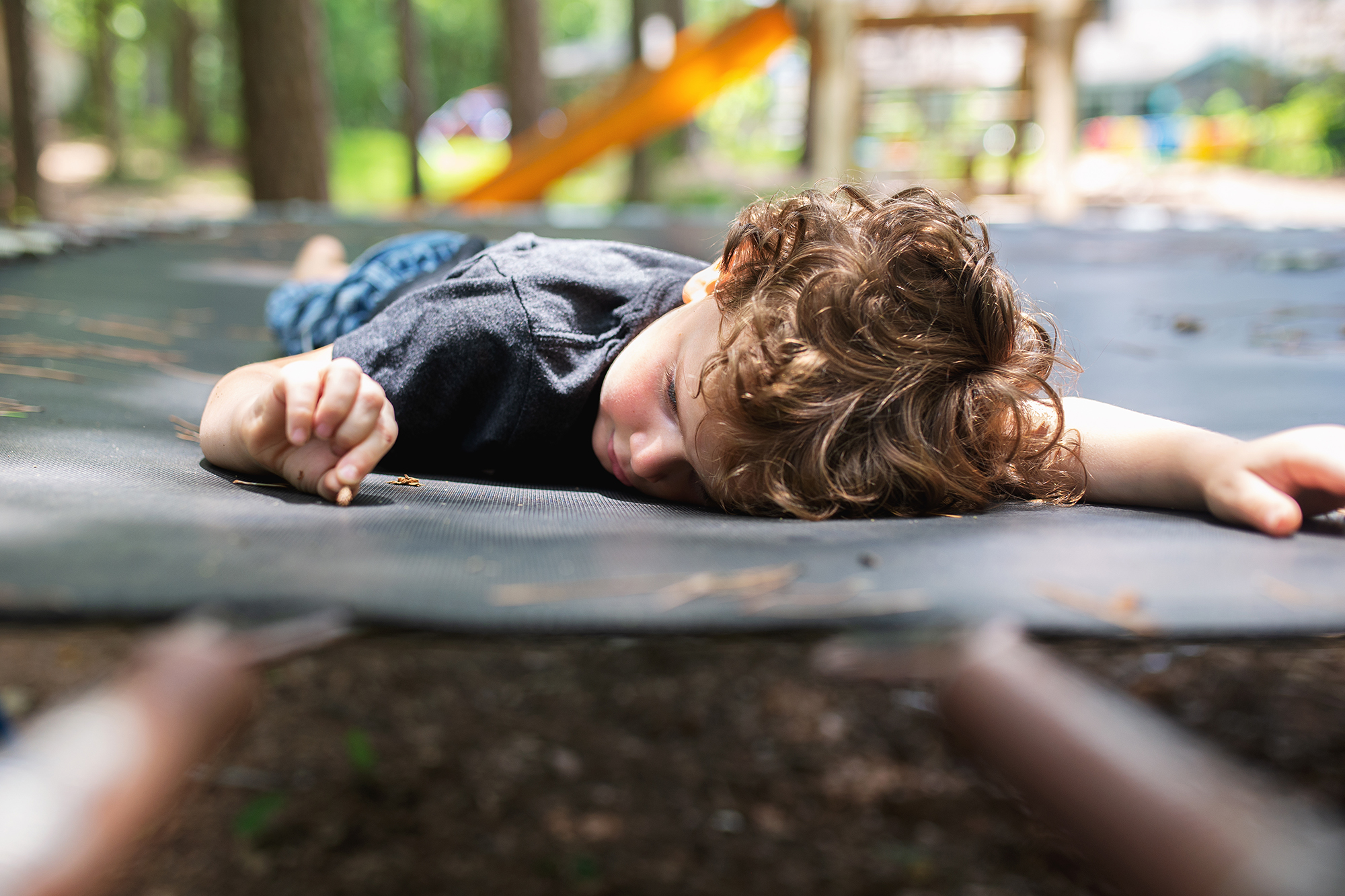 boy laying on trampoline - documentary family photography
